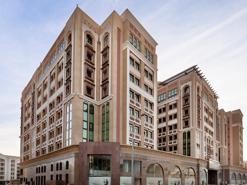 Facade view of La Maison Hotel, Doha, featuring a blue sky in the background, a hotel near Doha Corniche.
