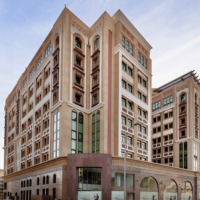 Facade view of La Maison Hotel, Doha, featuring a blue sky in the background, a hotel near Doha Corniche.