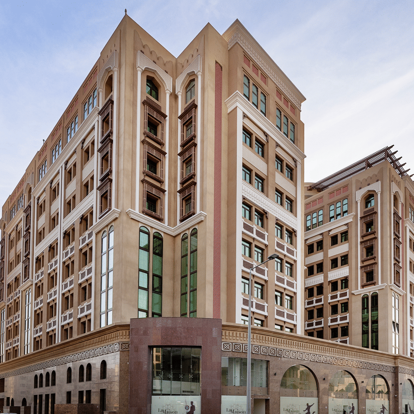 Facade view of hotel near Doha Airport set against a clear blue sky, showcasing a welcoming surrounding | La Maison Hotel, Doha