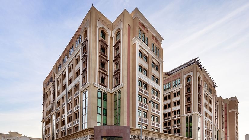 Facade image of La Maison Hotel, Doha with blue sky in the background