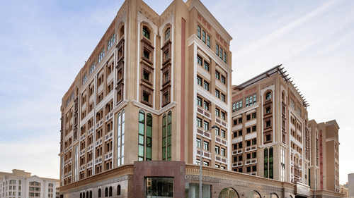 Facade view of La Maison Hotel, Doha, featuring a blue sky in the background, a hotel near Doha Corniche.