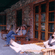 People relaxing on wooden lounge chairs along a stone-walled porch veranda.