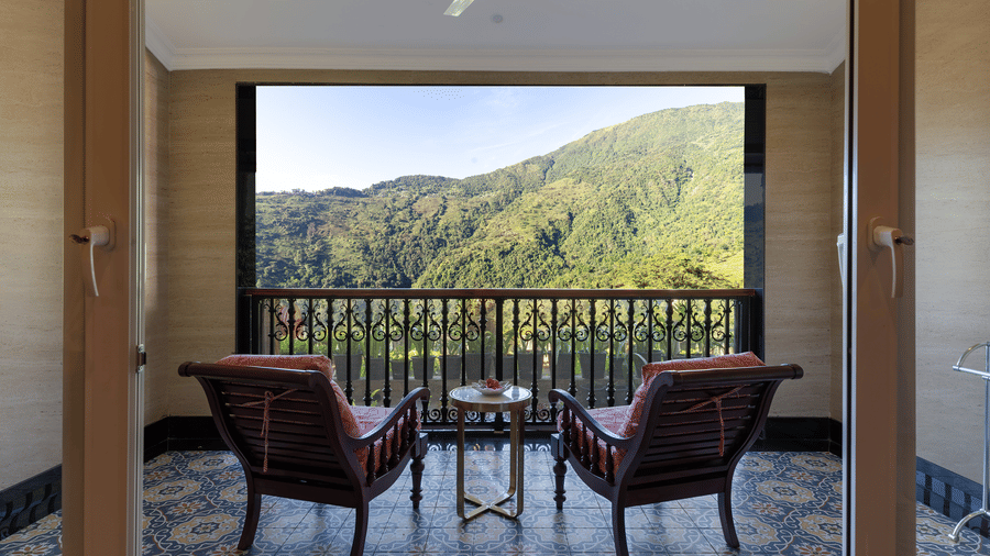 Covered private balcony with armchairs looking out over lush green hills at Mayfair Manor, Jungpana.