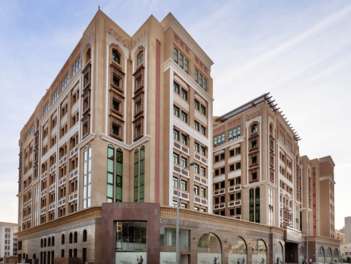 Facade view of La Maison Hotel, Doha, featuring a blue sky in the background, a hotel near Doha Corniche.