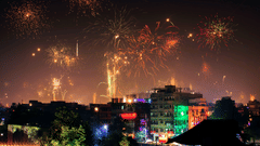 Beautiful firecrackers covering the entire night sky with buildings decorated with string lights in the foreground.