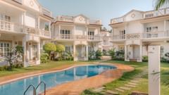 Swimming pool at Richmonde Ananta Elite, Goa featuring a serene poolside view with luxurious white villas in the background.