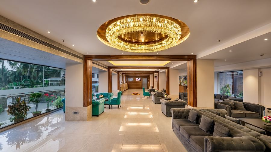 the corridor of our chandelier lit lobby with the seating area on side and a floor-to-glass windows on the other - Golden Tulip, Candolim, Goa