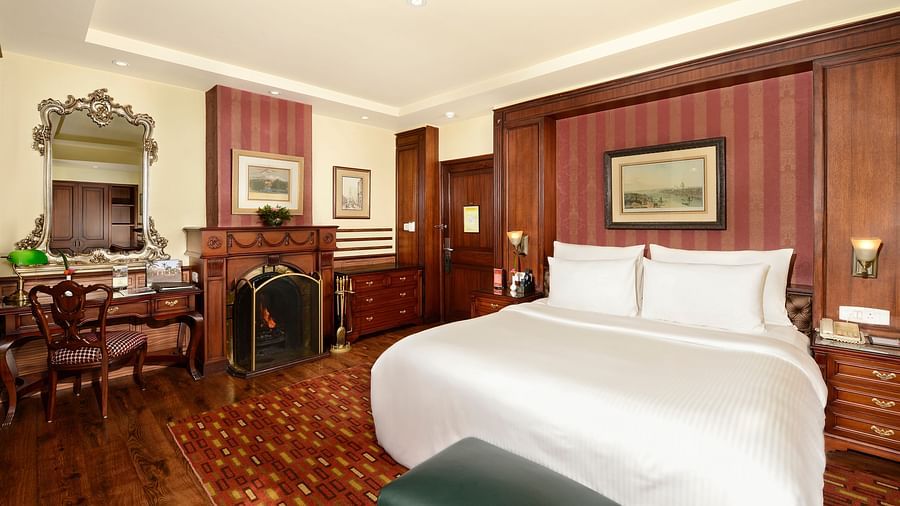 a king size bed and a fireplace to its left - Mayfair Hill Resort, Darjeeling 2