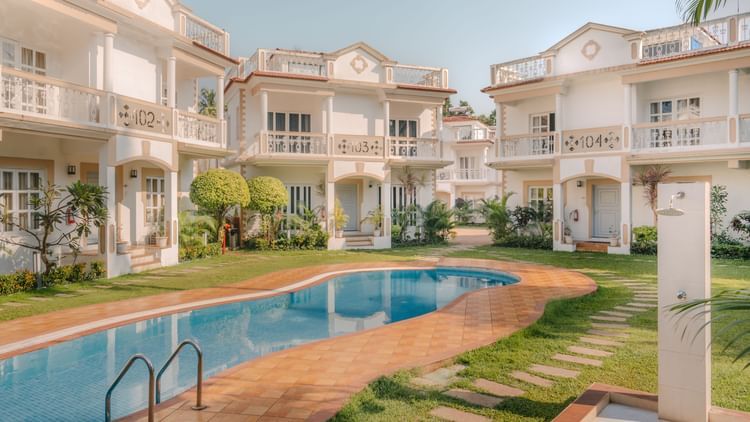 Swimming pool at Richmonde Ananta Elite, Goa featuring a serene poolside view with luxurious white villas in the background.