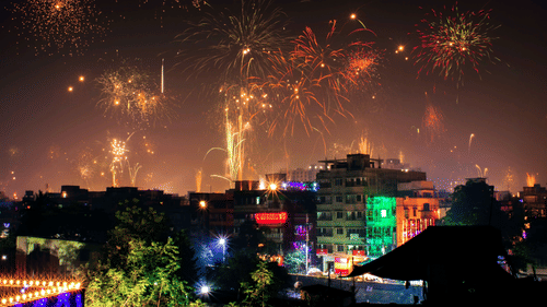 Beautiful firecrackers covering the entire night sky with buildings decorated with string lights in the foreground.