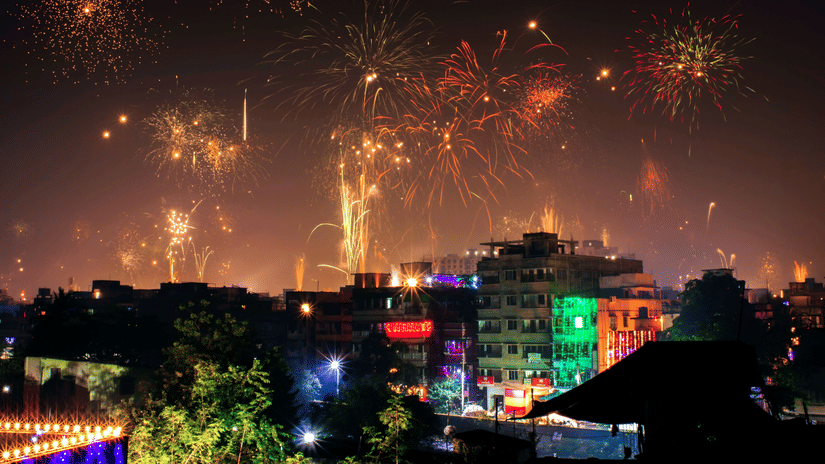 Beautiful firecrackers covering the entire night sky with buildings decorated with string lights in the foreground.
