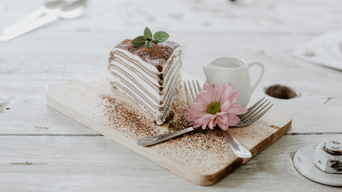 a slice of cake next to a cup