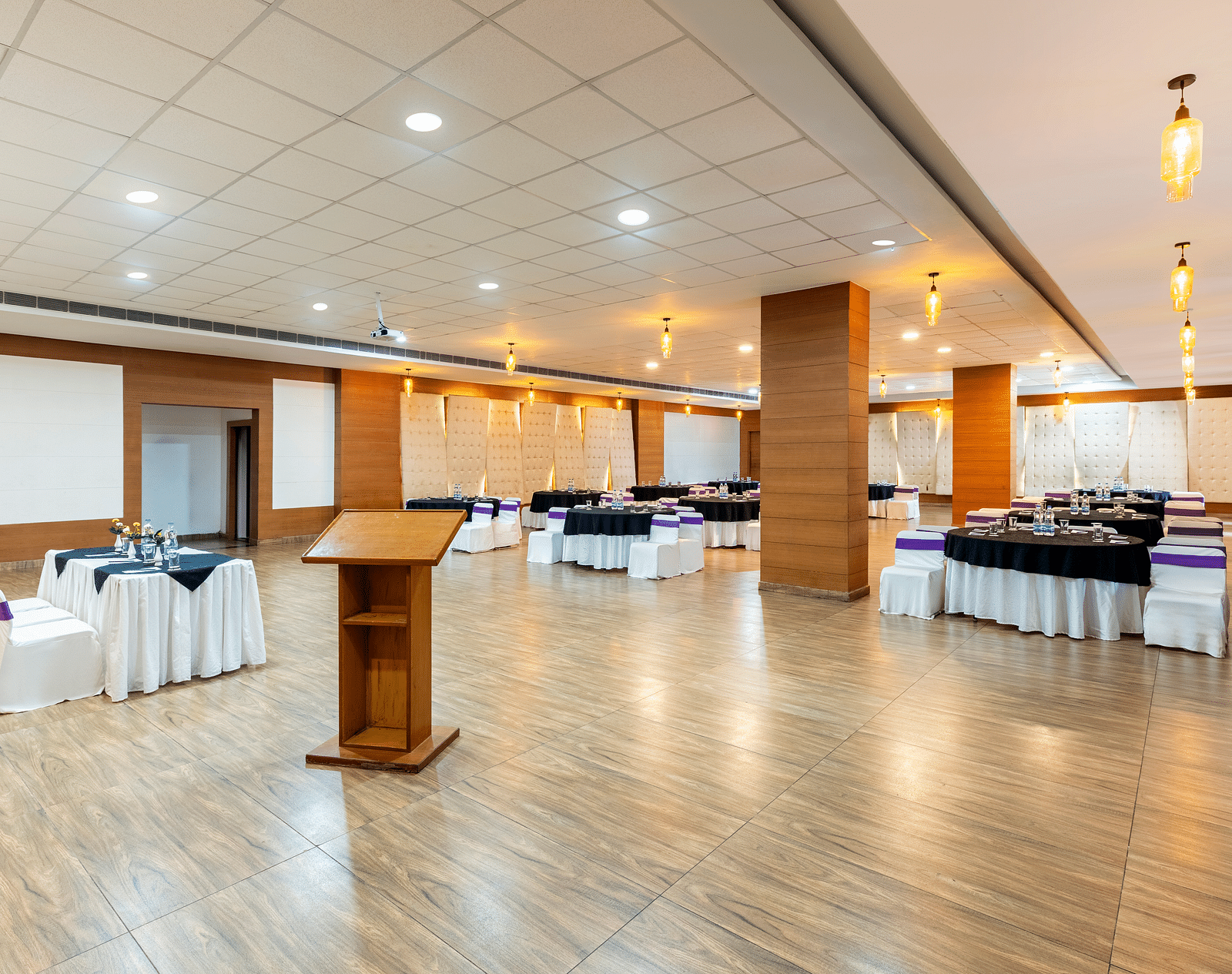A event hall arranged with a podium, tables, chairs, and a polished floor - Via Lakhela Resort & Spa