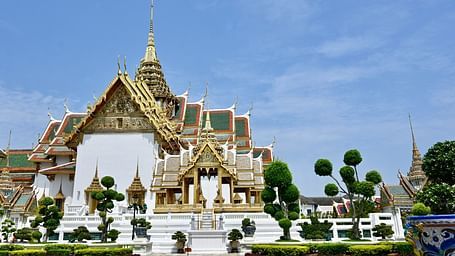 Overview of the grand palace in Bangkok with a garden in front of it.