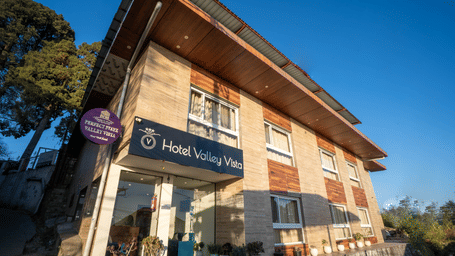 The exterior of a 2-storey hotel building with a slanted roof, a sign with hotel name as seen from a low angle on a sunny day | Perfectstayz Value Valley Vista
