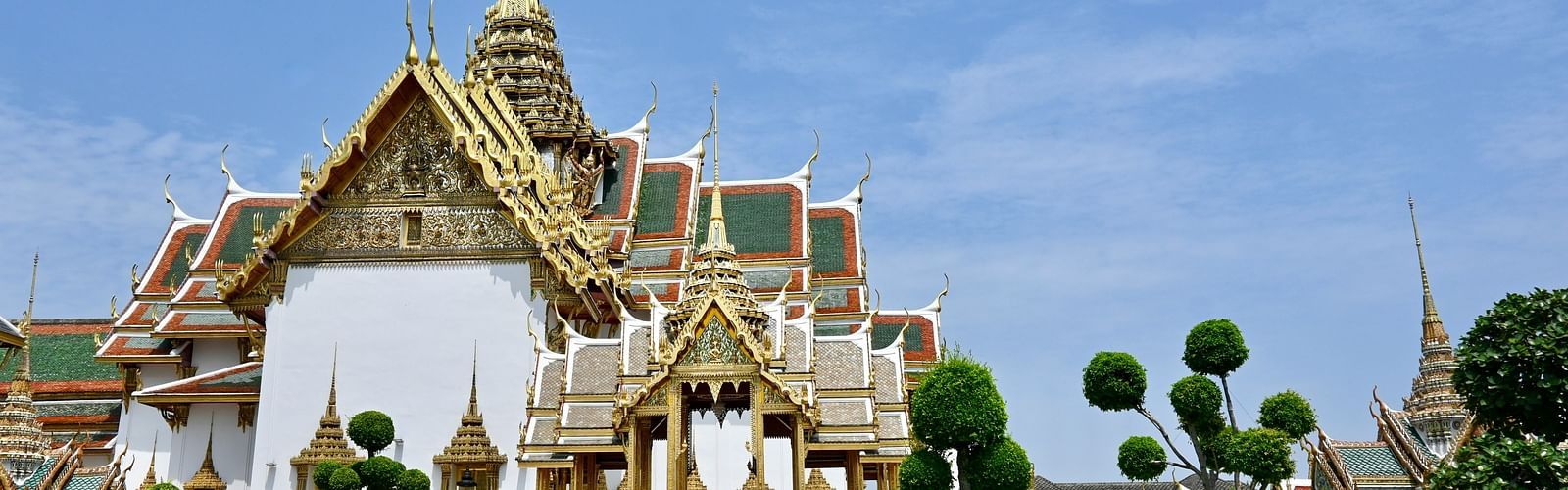 Overview of the grand palace in Bangkok with a garden in front of it.