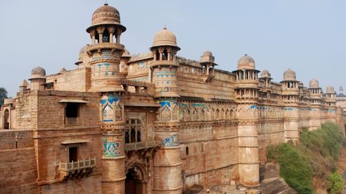 Gwalior Fort’s massive stone walls extending along the cliffside, overlooking the surrounding cityscape and greenery.