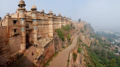 Gwalior Fort’s massive stone walls extending along the cliffside, overlooking the surrounding cityscape and greenery.