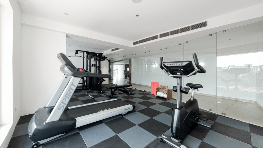 A gym room equipped with a treadmill and a stationary exercise bicycle on a checkered floor at Tiara by MPS.