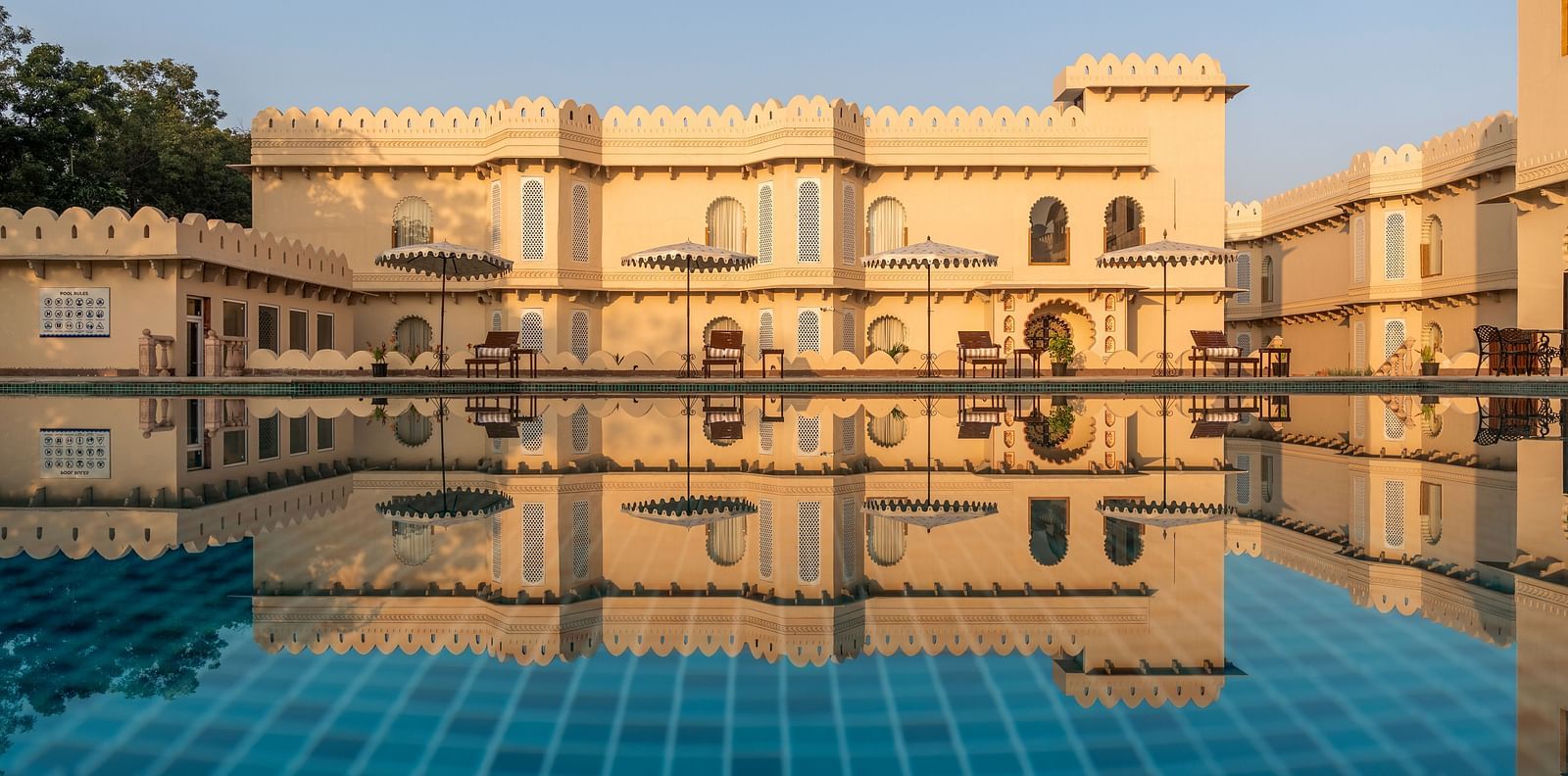 Grand palace reflected in a tranquil swimming pool at Kesar Bagh Palace.