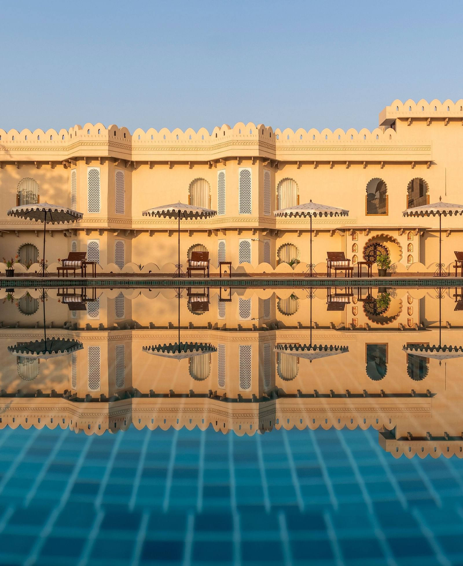 Grand palace reflected in a tranquil swimming pool at Kesar Bagh Palace.