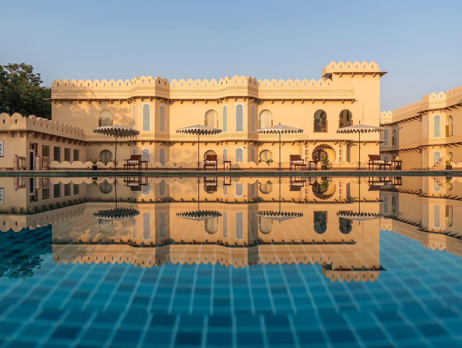 Grand palace reflected in a tranquil swimming pool at Kesar Bagh Palace.
