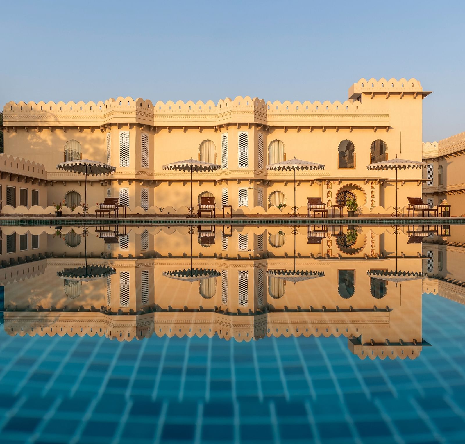 Grand palace reflected in a tranquil swimming pool at Kesar Bagh Palace.