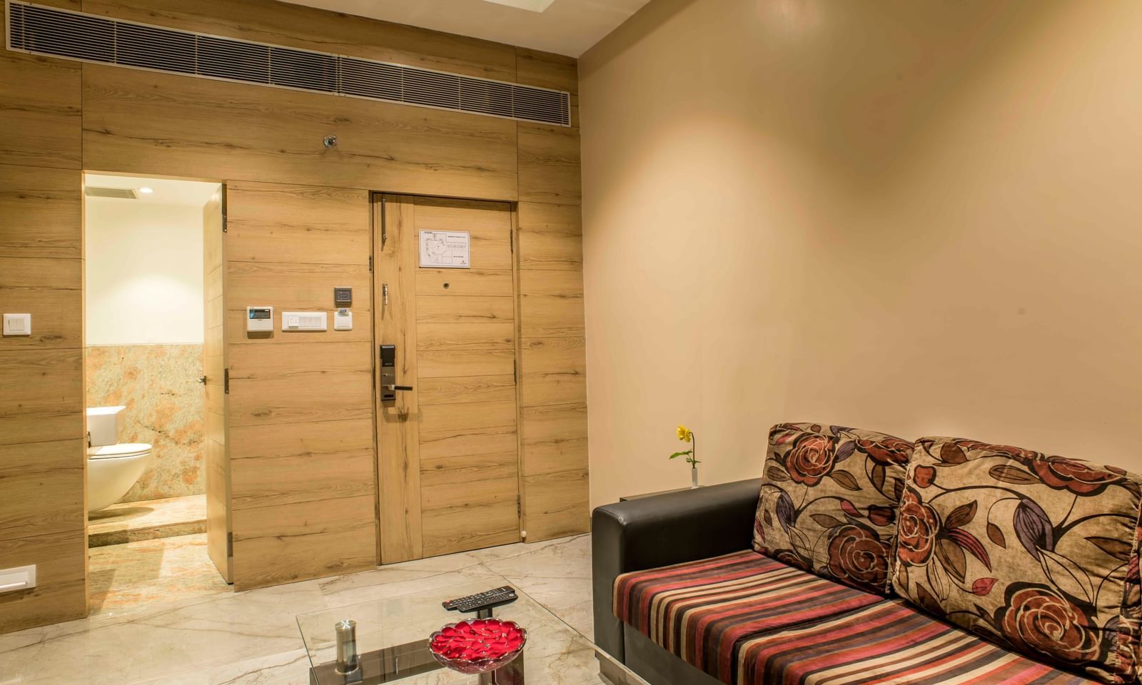 Hotel suite featuring a seating area with a patterned sofa and a separate bedroom | The Citi Residenci Hotel Durgapur