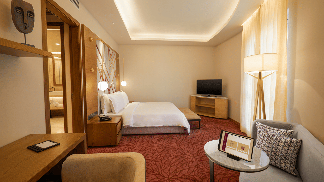 The Suite at Residency Towers, Chennai featuring a double bed, a  television, a seating area, a work desk, and carpet flooring.