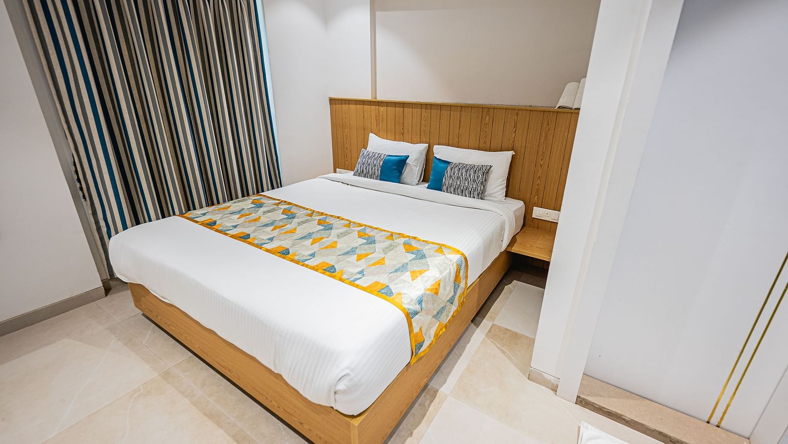 An image of a bedroom featuring a double size bed at Indie Stays Studio, Chembur which  also has a bedside table and a window next to it