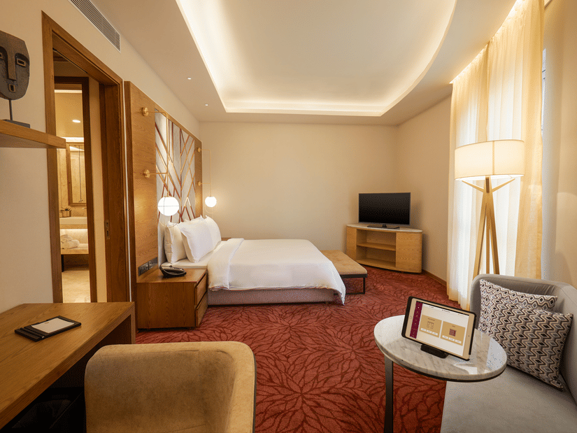 The Suite at Residency Towers, Chennai featuring a double bed, a  television, a seating area, a work desk, and carpet flooring.