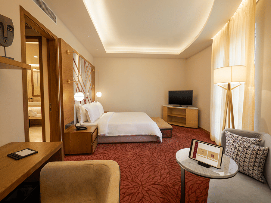 The Suite at Residency Towers, Chennai featuring a double bed, a  television, a seating area, a work desk, and carpet flooring.