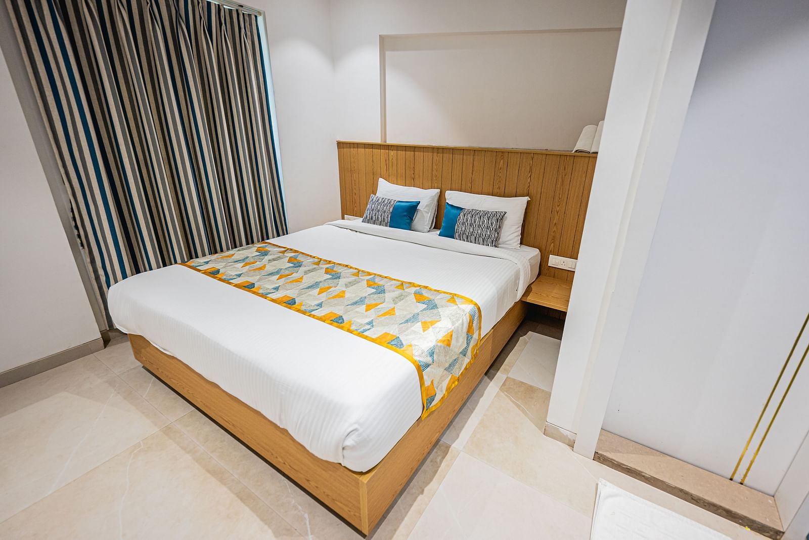 An image of a bedroom featuring a double size bed at Indie Stays Studio, Chembur which  also has a bedside table and a window next to it
