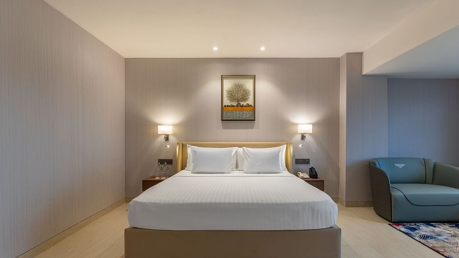  Contemporary bedroom with king bed, bedside lights, sofa set, and soft neutral tones at Clarks Inn Suites, Hyderabad