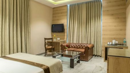 Hotel room with a single bed, a seating area, and a television at The Citi Residenci Hotel Durgapur