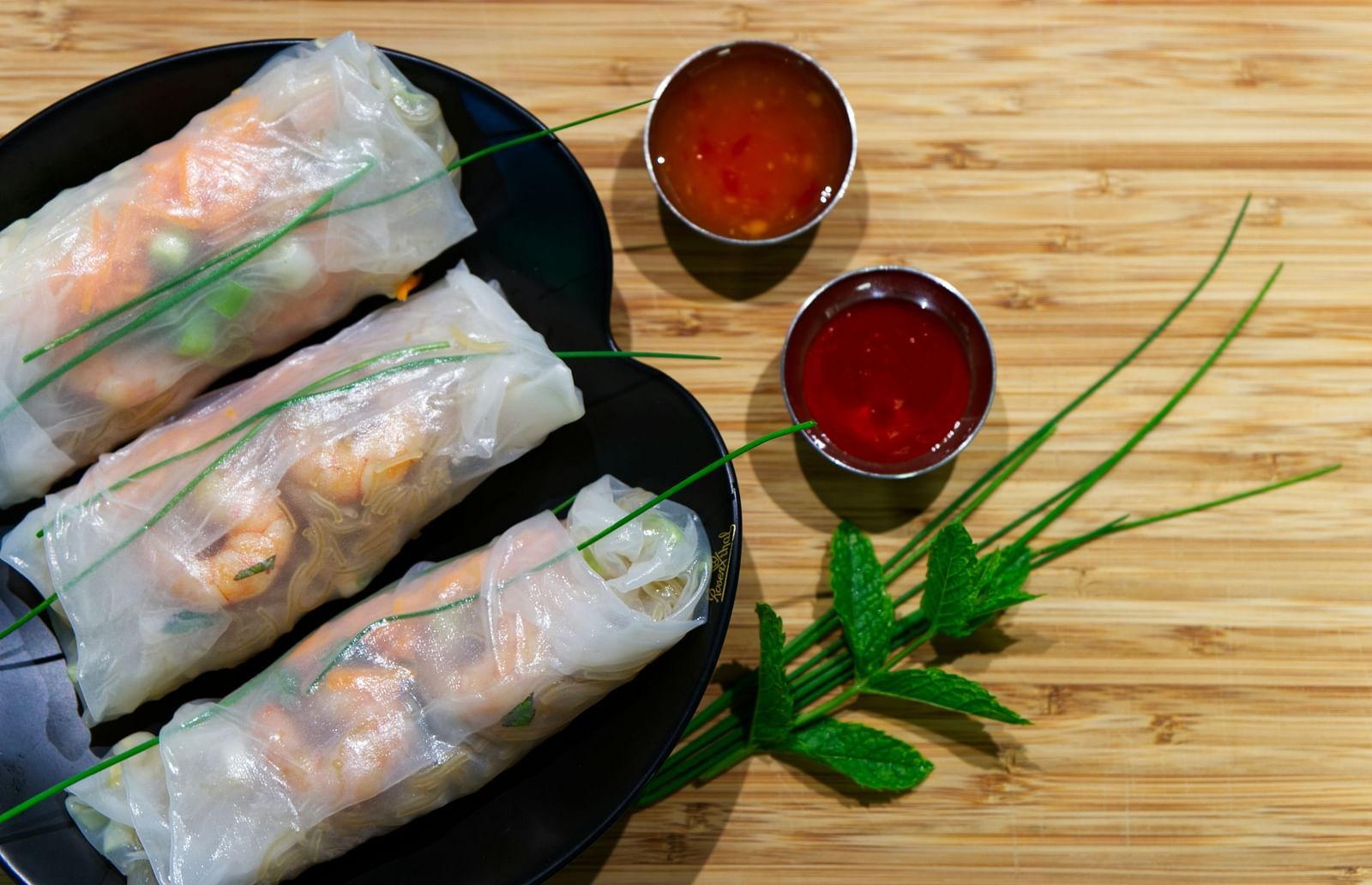 spring rolls made of rice paper wrapped with shrimps placed on a plate, served with Sause on the side