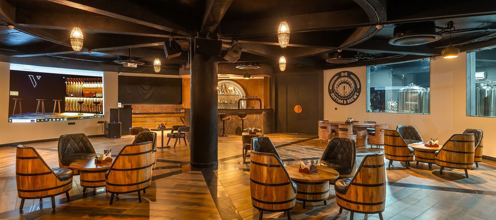 Rhythm & Brews furnished with wooden chairs and tables, creating a warm and inviting ambience at The Qualia Resort Club & Brewery, Udaipur.