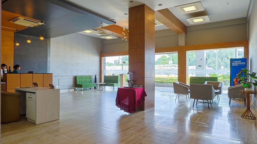 Lobby with seating, wooden pillars and large glass windows at Max Hotel Prayagraj.
