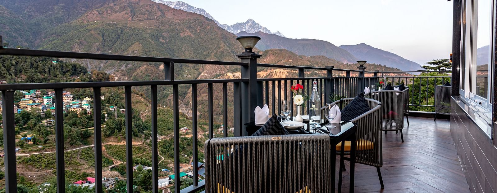 An image of the outdoor dining area with seating arrangement and scenic mountain views as the backdrop - The Belvedere Himalayan Retreat, McLeodganj