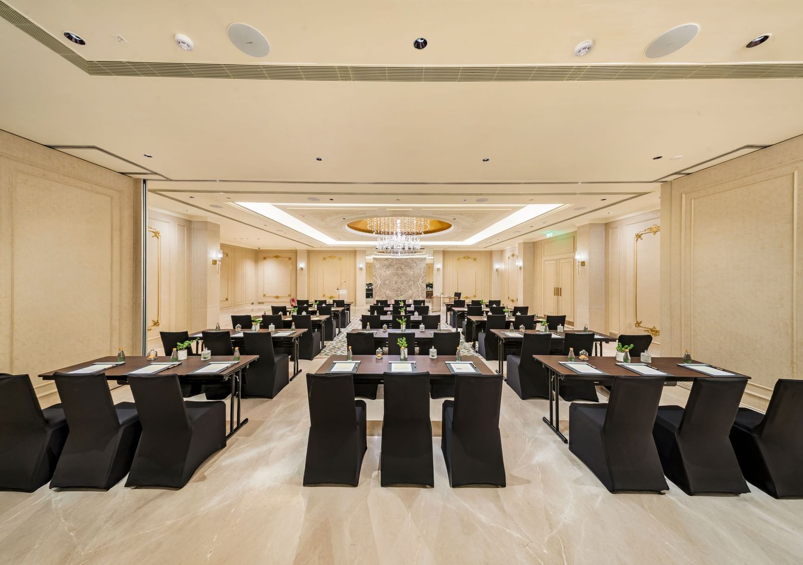 A wide view of a formal meeting or dining space at Grand Chennai by GRT Hotels dark rectangular tables and chairs arranged for efficient use. The neutral color palette and simple yet elegant decor create a refined and professional environment.
