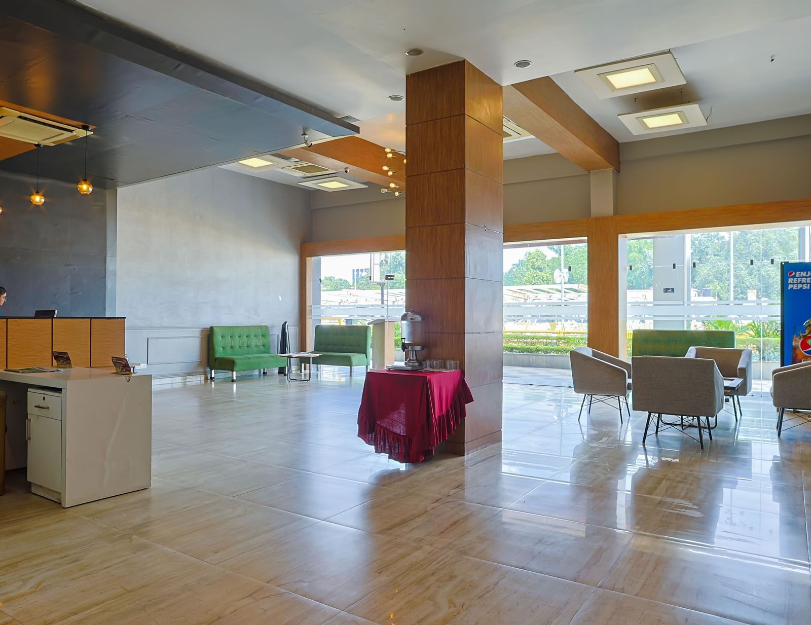 Lobby with seating, wooden pillars and large glass windows at Max Hotel Prayagraj.