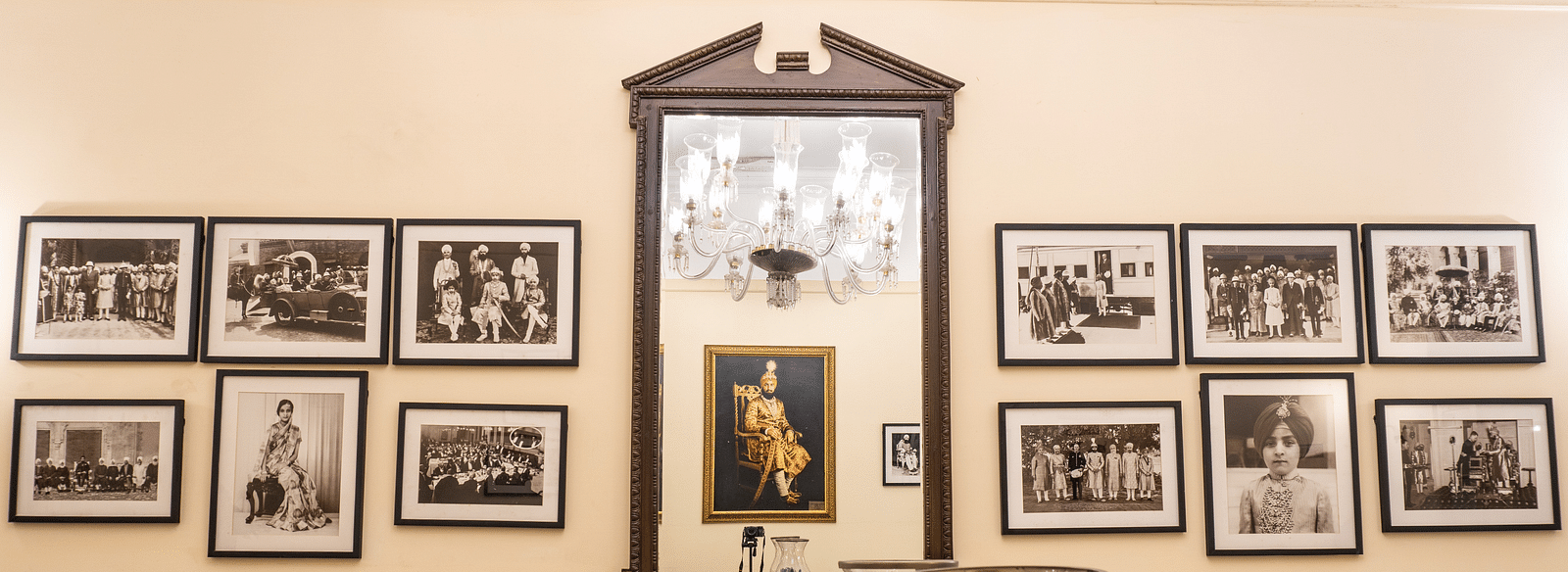 The wall adorned with a Maharaja painting and other smaller artworks illustrating the history of The Claridges Nabha Residence, Mussoorie