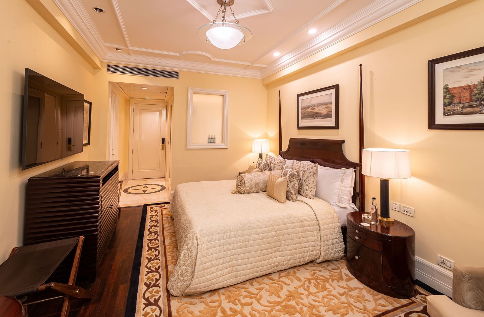 image of our heritage parlour room from a corner angle showing the plush soft bed and a wall mounted television placed in front of it - The Claridges New Delhi