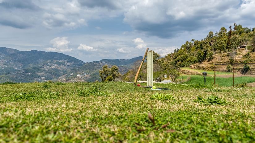  Picture showing a cricket bat, a Set of Stumps, and a red ball along with  a Badminton Racquet and a Shuttle.