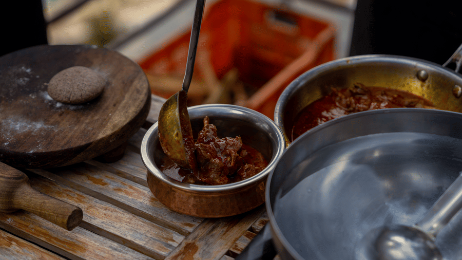 Food preparation at BluSalzz Escapade Resort, Lansdowne, shows a ladle scooping contents from a bowl next to other cooking vessels and a rolling board.