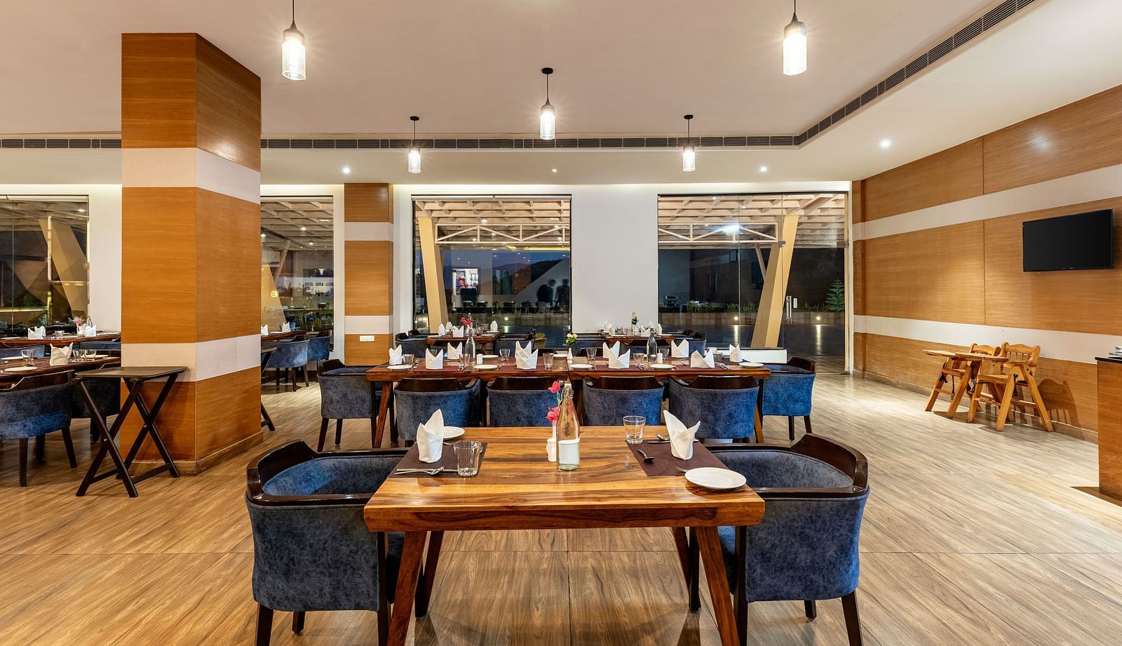 Restaurant with wooden tables, blue chairs, and a decorative wall - Via Lakhela Resort & Spa