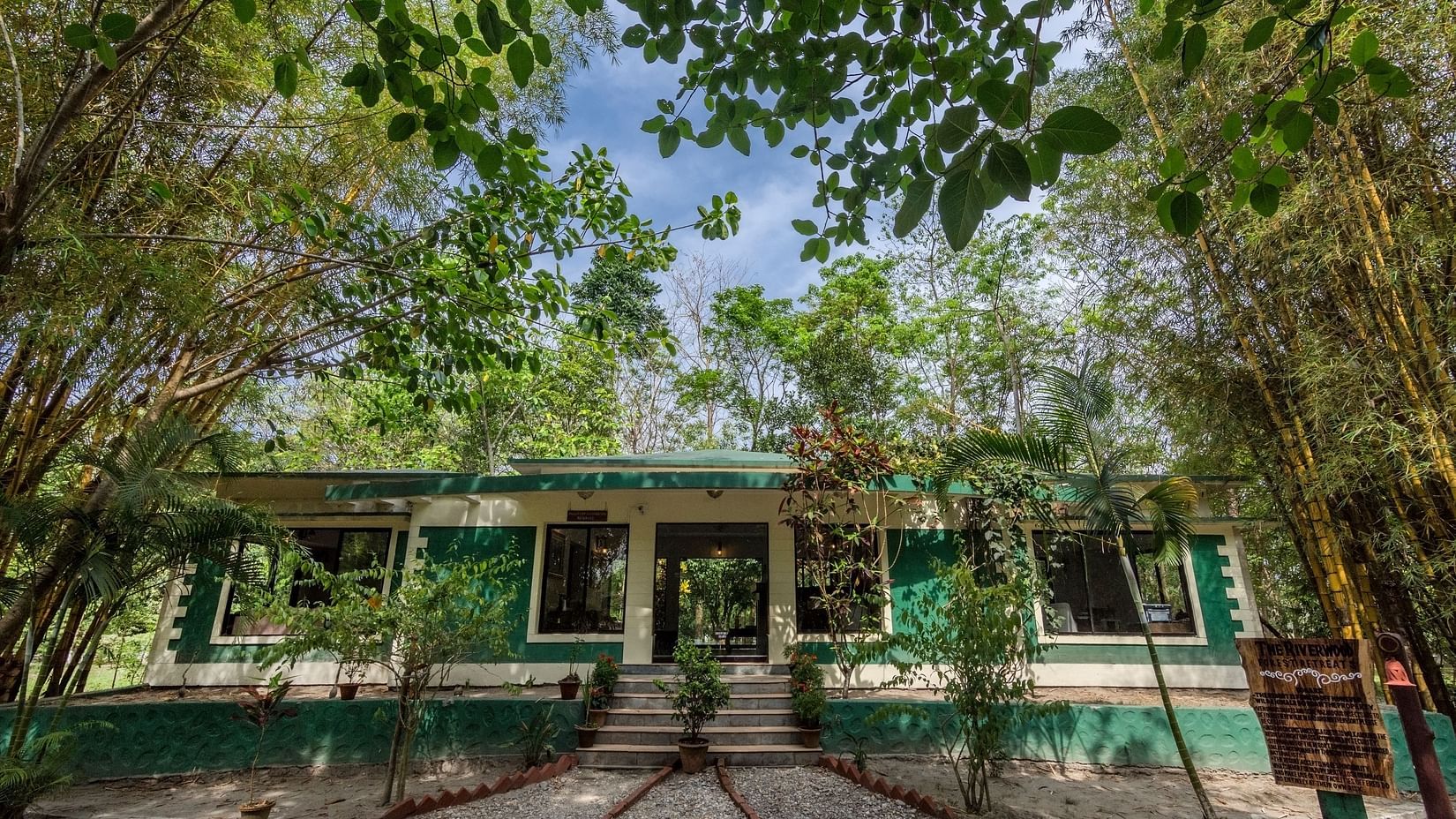Exterior of the reception surrounded by trees at The Riverwood Forest Retreat, Dooars
