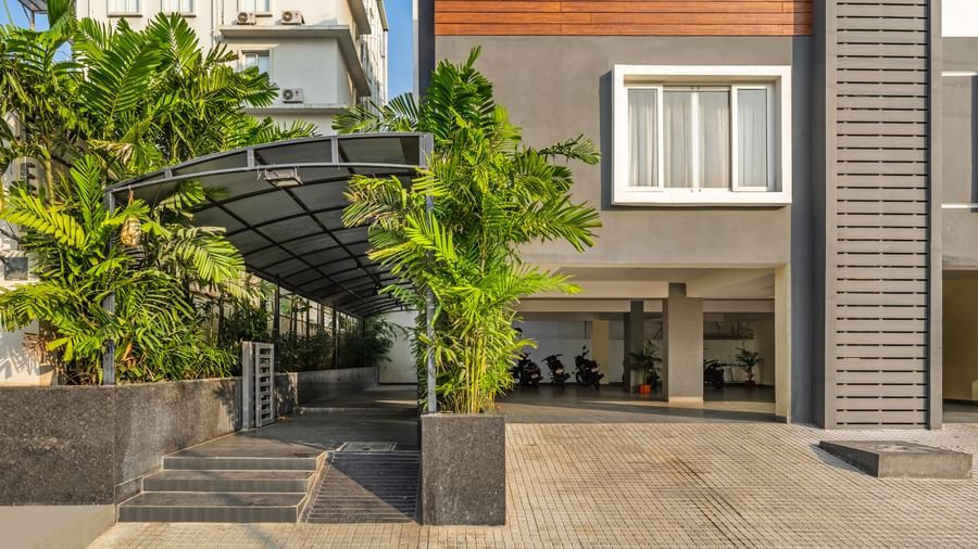 The entrance of Destino by Monday Hotels, Gachibowli, showing a paved driveway, a small staircase, and lush green plants.