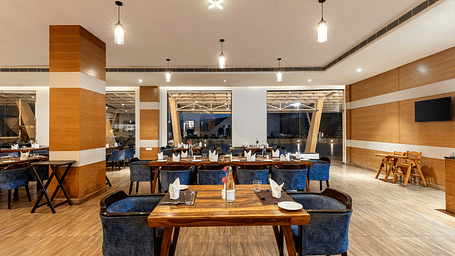 Restaurant with wooden tables, blue chairs, and a decorative wall - Via Lakhela Resort & Spa