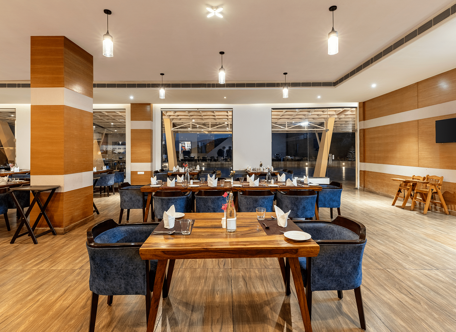 Restaurant with wooden tables, blue chairs, and a decorative wall - Via Lakhela Resort & Spa